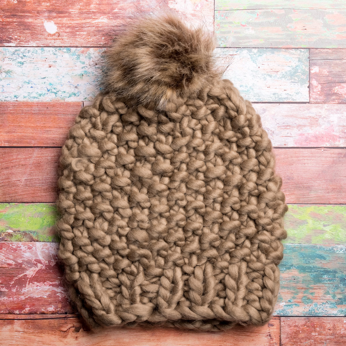A generous faux fur pom-pom looks like real fur, on a colorful chunky knit hat.