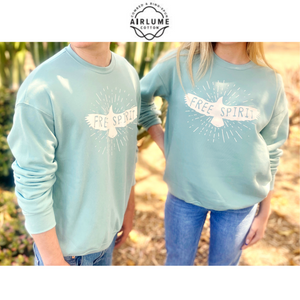 Torsos of a man and woman both wearing  light blue, long-sleeved sweatshirts that have a graphic of a soaring bird with the words "FREE SPIRIT" across its wings.